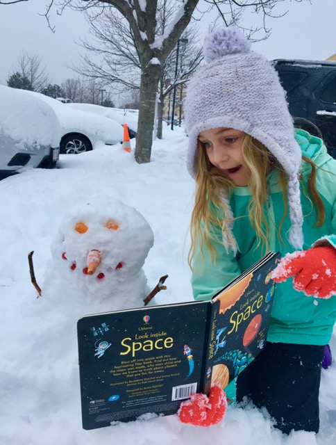 girl reading to snowperson